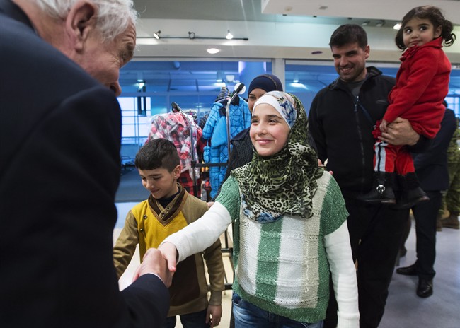 John McCallum, left, Minister of Immigration, Refugees and Citizenship, greets Khloud, centre, along with her family at Pearson International Airport in Toronto on Monday, February 29, 2016. THE CANADIAN PRESS/Nathan Denette.