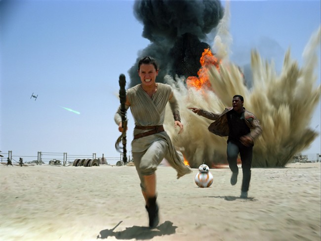 This photo provided by Disney shows Daisey Ridley as Rey, left, and John Boyega as Finn, in a scene from the new film, "Star Wars: The Force Awakens.".