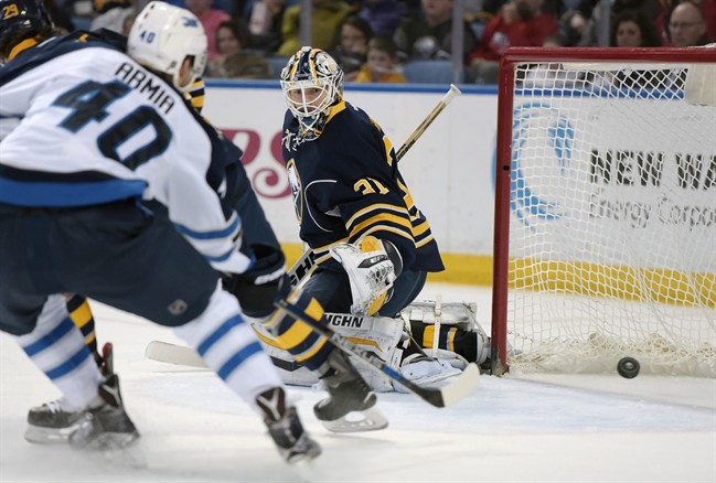 Winnipeg Jets forward Joel Armia deflects the puck wide of the goal as Buffalo Sabres goaltender Chad Johnson defends during the second period.
