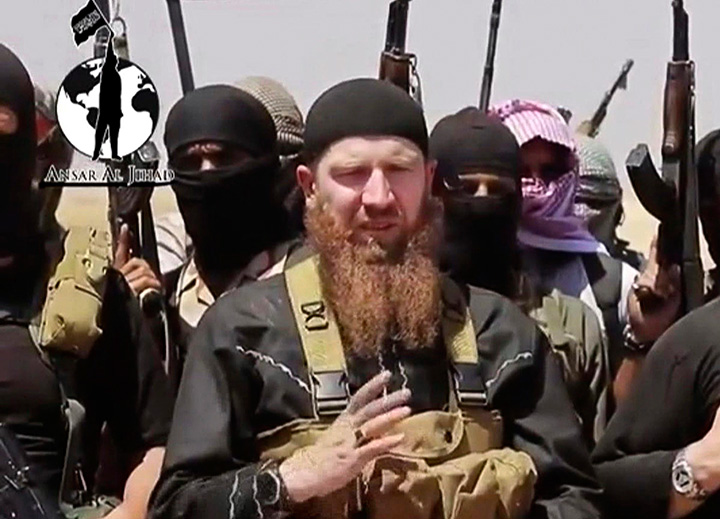 This image made from undated video posted during the weekend of June 28, 2014 on a social media account frequently used for communications by the Islamic State, shows Omar al-Shishani standing among a group of fighters as they declare the elimination of the border between Iraq and Syria. 
