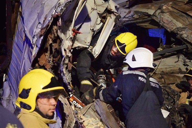 In this photo made available by the Oman Police, Omani civil defence workers rescue people from a damaged bus after a crash, near Nahdah area on the road connecting the cities of Fahud and Ibriin, in Oman, Tuesday March 1, 2016. 