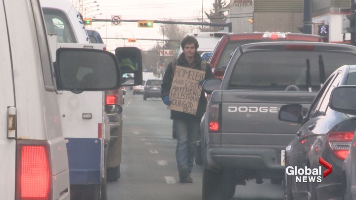 29-year-old David Levuc strolls between vehicles stopped at a red light on 16th Avenue North, begging for change.