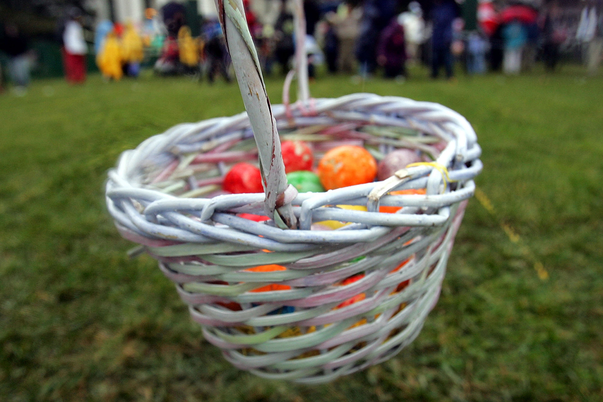 Coloured eggs sit in a basket .