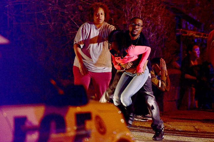 A woman is held back as police respond to the scene of a deadly shooting in Wilkinsburg, Pa., Thursday, March 10, 2016.