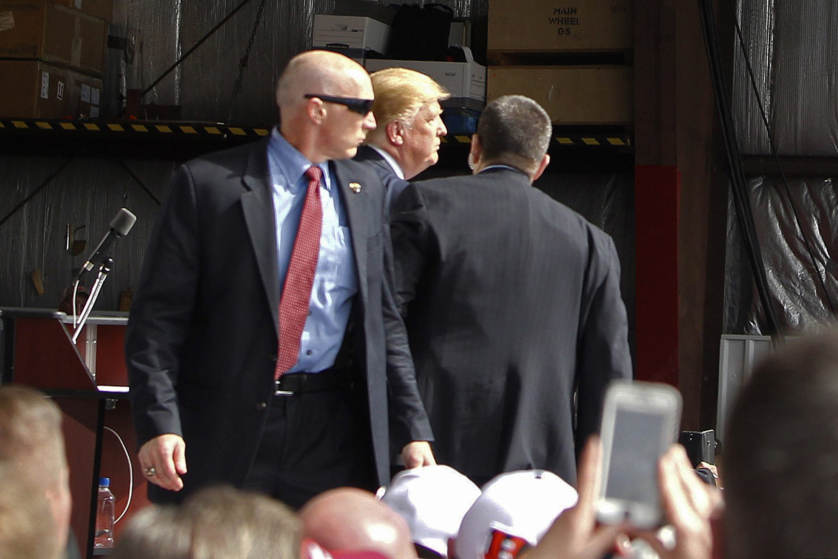 Secret Service agents guard Republican presidential candidate, businessman Donald Trump, on the stage after a man tried to breach the security buffer at his campaign event at the Wright Brothers Aero Hangar Saturday, March 12, 2016, in Vandalia, Ohio. 