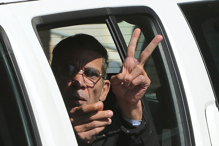 EgyptAir plane hijacking suspect Seif Eddin Mustafa flashes the victory sign as he leaves a court in a police car after a remand hearing as authorities investigate him on charges including hijacking, illegal possession of explosives and abduction in the Cypriot coastal town of Larnaca Wednesday, March 30, 2016.