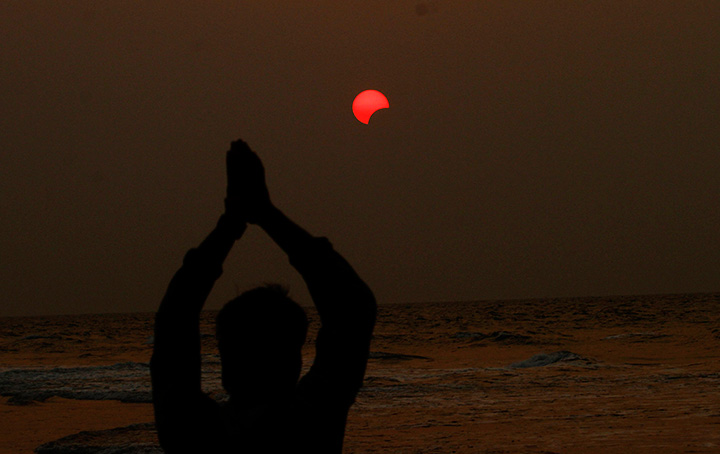 An Indian fisherman prays to a partial solar eclipse seen in the sky over Bay of Bengal in Konark, 60 kilometers from eastern Indian city Bhubaneswar, Wednesday, March 9, 2016.