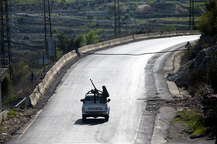 Syrian troops ride on a pickup truck with a mounted machine gun on a road near Latakia in Syria, Wednesday, March 2, 2016. 