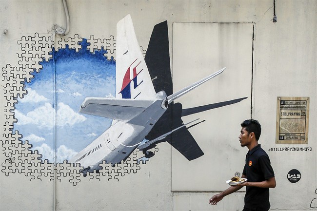 In this Feb. 23, 2016 file photo, a waiter walks past a mural of Malaysia Airlines Flight 370, in Shah Alam outside Kuala Lumpur, Malaysia.