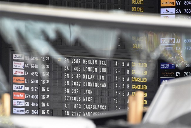 A departure and arrivals board is seen behind a blown out window at Zaventem Airport in Brussels on Wednesday, March 23, 2016. Belgian authorities were searching Wednesday for a top suspect in the country's deadliest attacks in decades, as the European Union's capital awoke under guard and with limited public transport after scores were killed and injured in bombings on the Brussels airport and a subway station.