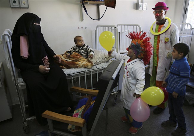 In this Thursday, March 17, 2016 photo, Palestinian clown doctor Alaa Miqdad, center, gives 3-year-old Abdallah Saleem a balloon, in the department of kidney diseases at Al-Rantisi children’s hospital in Gaza City. Miqdad and his partner visit three medical centers in the Gaza Strip a week and spend two days at Al-Rantisi, a specialized hospital for children with chronic illnesses. “As much as we can, we try to let the child respond to us to reach his heart; his insides,” Majed said. (AP Photo/Adel Hana).
