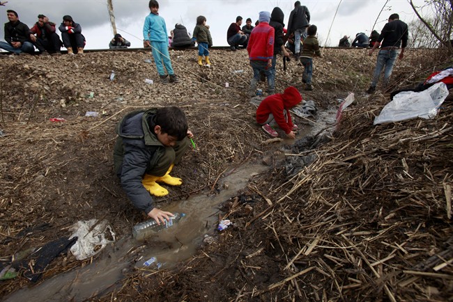 Syrian children play in muddy water in an improvised camp on the border line between Macedonia and Serbia, near northern Macedonian village of Tabanovce, Tuesday, March 8, 2016. Former prime minister Paul Martin says the G20 needs to expand its scope to help in times of crises.