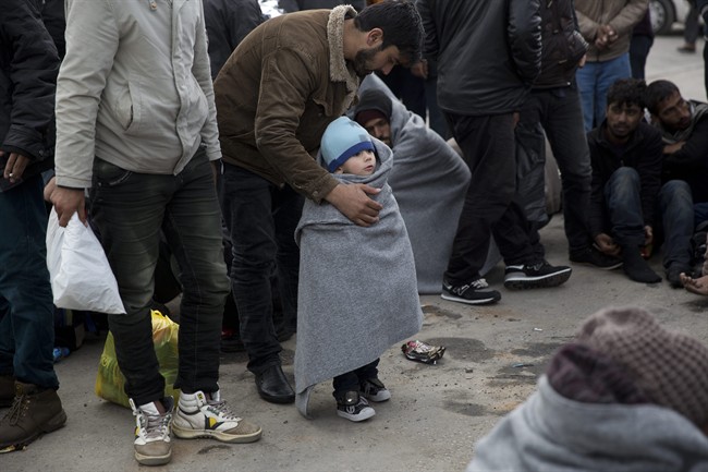 A man covers his son with a blanket at the port of Mytilini following a rescue operation by the Greek coast guard of 127 refugees and migrants off the shores of the Greek island of Lesbos, Tuesday, March 22, 2016. 