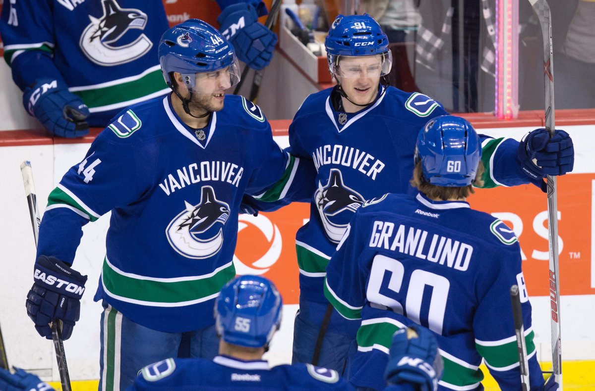 Vancouver Canucks' Matt Bartkowski, left, Jared McCann, top right, and Markus Granland, of Finland, celebrate McCann's goal against the Los Angeles Kings during the second period of an NHL hockey game in Vancouver, B.C., on Monday April 4, 2016. 