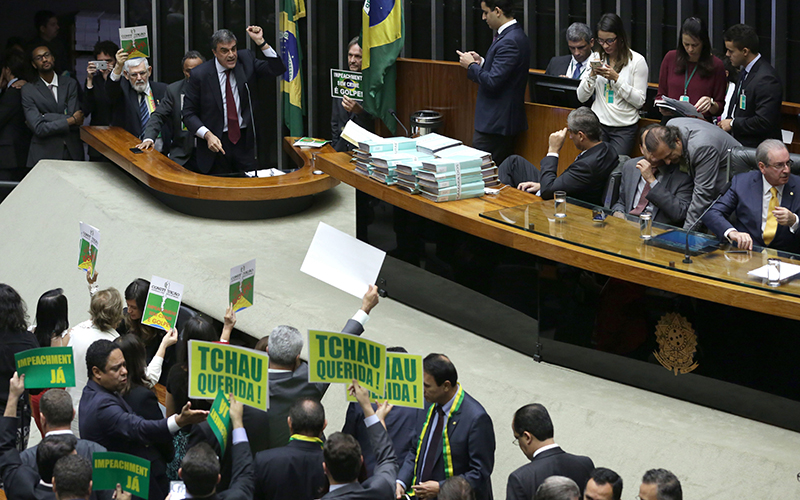 Brazil's Attorney General Jose Eduardo Cardozo, top left, presents the defense of Brazil's President Dilma Rousseff in the Chamber of Deputies, as opposition lawmakers hold signs that read in Portuguese "Goodbye dear" and "Impeachment now" in Brasilia, Brazil, Friday, April 15, 2016.  