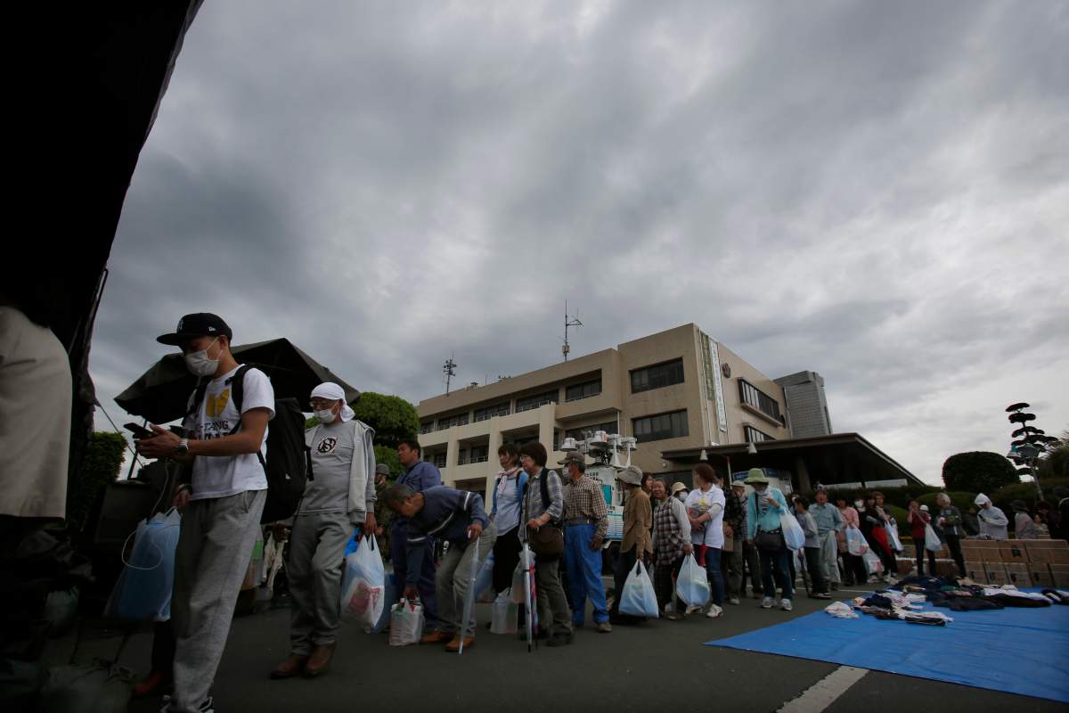Local residents wait in line for rations of cooked rice at a distribution center in Mashiki, Kumamoto prefecture, southwestern Japan, Saturday, April 16, 2016.