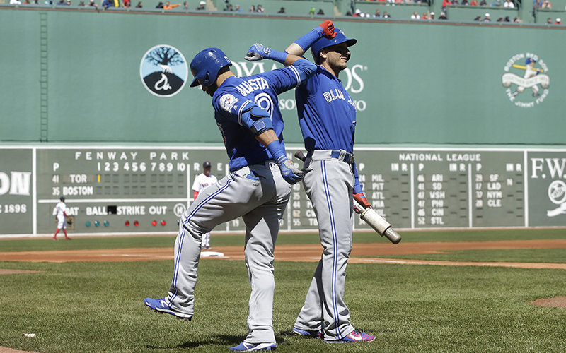 Toronto Blue Jays' Jose Bautista, left, celebrates with teammate Troy Tulowitzki, right, after hitting a home run in the first inning of a baseball game against the Boston Red Sox, at Fenway Park, Sunday, April 17, 2016, in Boston. 