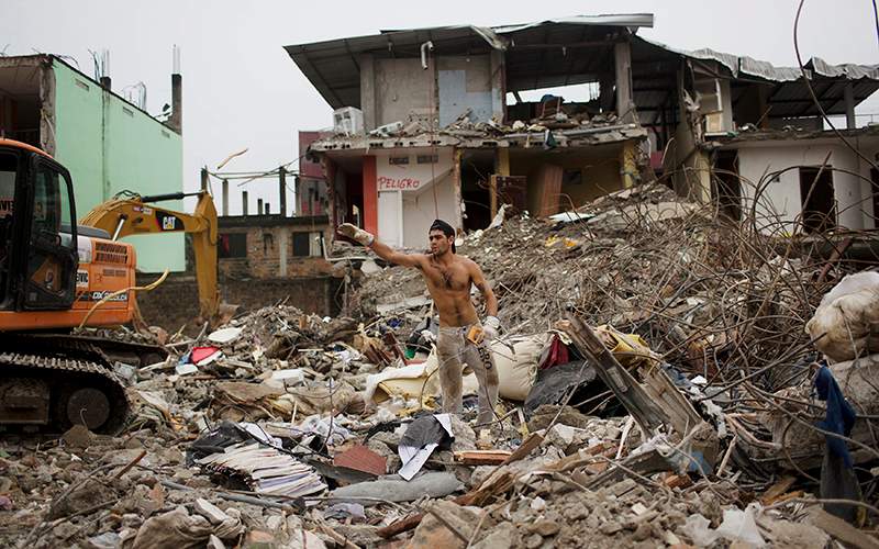 A man recovers cables to recycle, amid de debris of a destroyed building one week after the devastating earthquake in Pedernales, Ecuador, Saturday, April 23, 2016. 