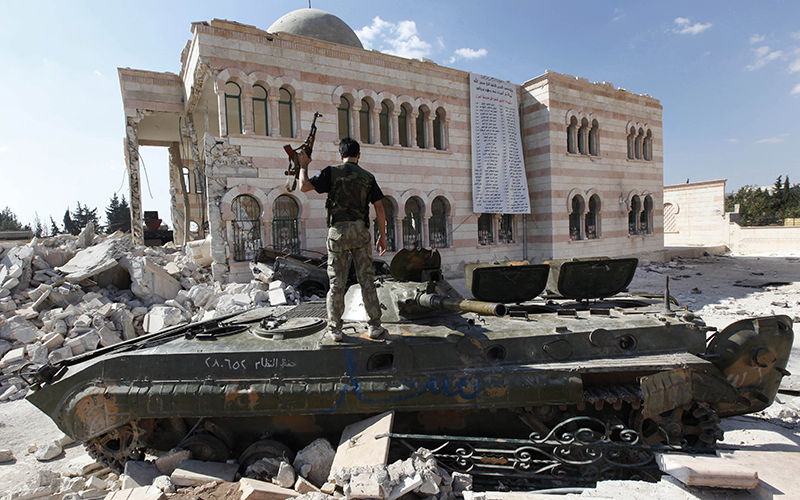 A Free Syrian Army soldier stands on a damaged Syrian military tank in front of a damaged mosque, which were destroyed during fighting with government forces, in the Syrian town of Azaz, on the outskirts of Aleppo. 