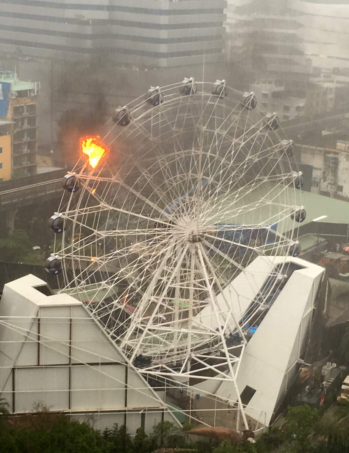 An empty passenger car of a Ferris wheel burns at a newly opened dinosaur theme park in central Bangkok, Thailand, Saturday, April 30, 2016.