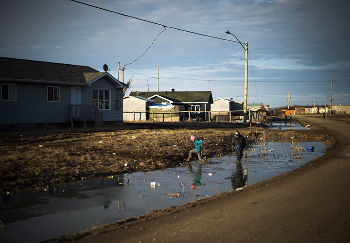 Indigenous children play in a water- filled ditch in the northern Ontario First Nations reserve in Attawapiskat, Ont., on Tuesday, April 19, 2016. 