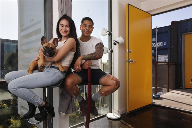 Patrick Tupas, right, with his wife, Maria Real-Tupas, who is holding their dog Moon Moon Fitzgerald, sit in the living room at their shipping container apartment in Phoenix. 