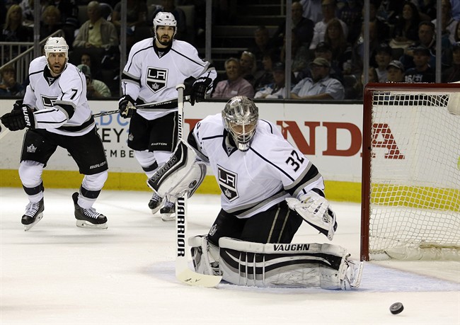 Los Angeles Kings goalie Jonathan Quick, right, watches a shot from the San Jose Sharks sail wide during the first period of Game 4 of an NHL hockey first-round Stanley Cup playoff series Wednesday, April 20, 2016, in San Jose, Calif. At left are Kings' Rob Scuderi (7) and Jake Muzzin (6).