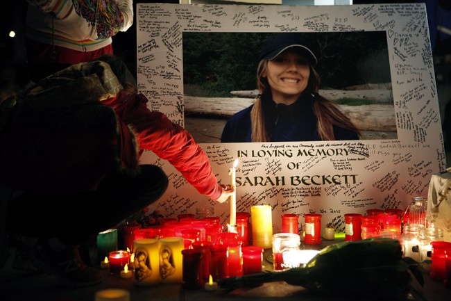 A supporter leaves a candle amongst others on a memorial during a candlelight vigil to remember West Shore RCMP Const. Sarah Beckett at Veteran's Memorial Park, in Langford, B.C., on Sunday, April 10, 2016.