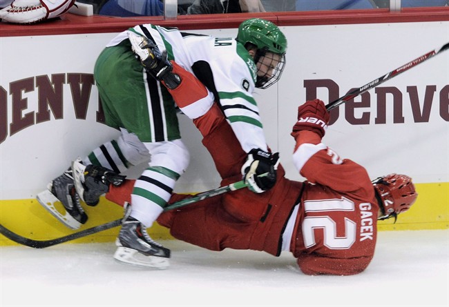 North Dakota's Drake Caggiula, left, checks Miami's Alex Gacek (12)during the first period in an NCAA hockey game in the semifinals of the National Collegiate Hockey Confernece tournament in Minneapolis, Friday, March 21, 2014.