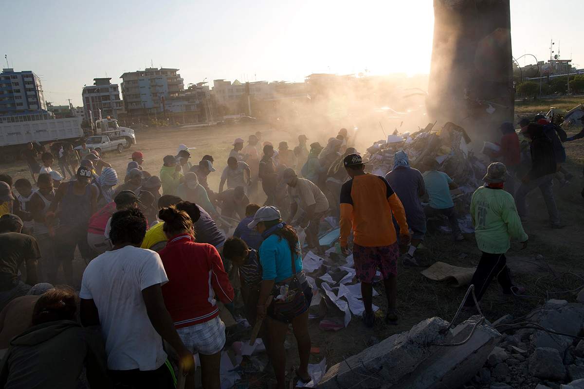 Residents comb through a post-earthquake debris field to salvage recyclable material as a dump truck unloads its cargo, in Manta, Ecuador, Wednesday, April 20, 2016.
