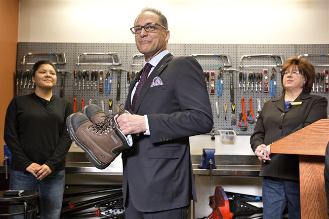 Alberta Finance MinisterJoe Ceci prepares to donate work boots to Women Building Futures student Kim Brertton, left, as CEO of Women Building Futures JudyLynn Archer looks on during a pre-budget photo opportunity in Edmonton, on Monday April 13, 2016. 