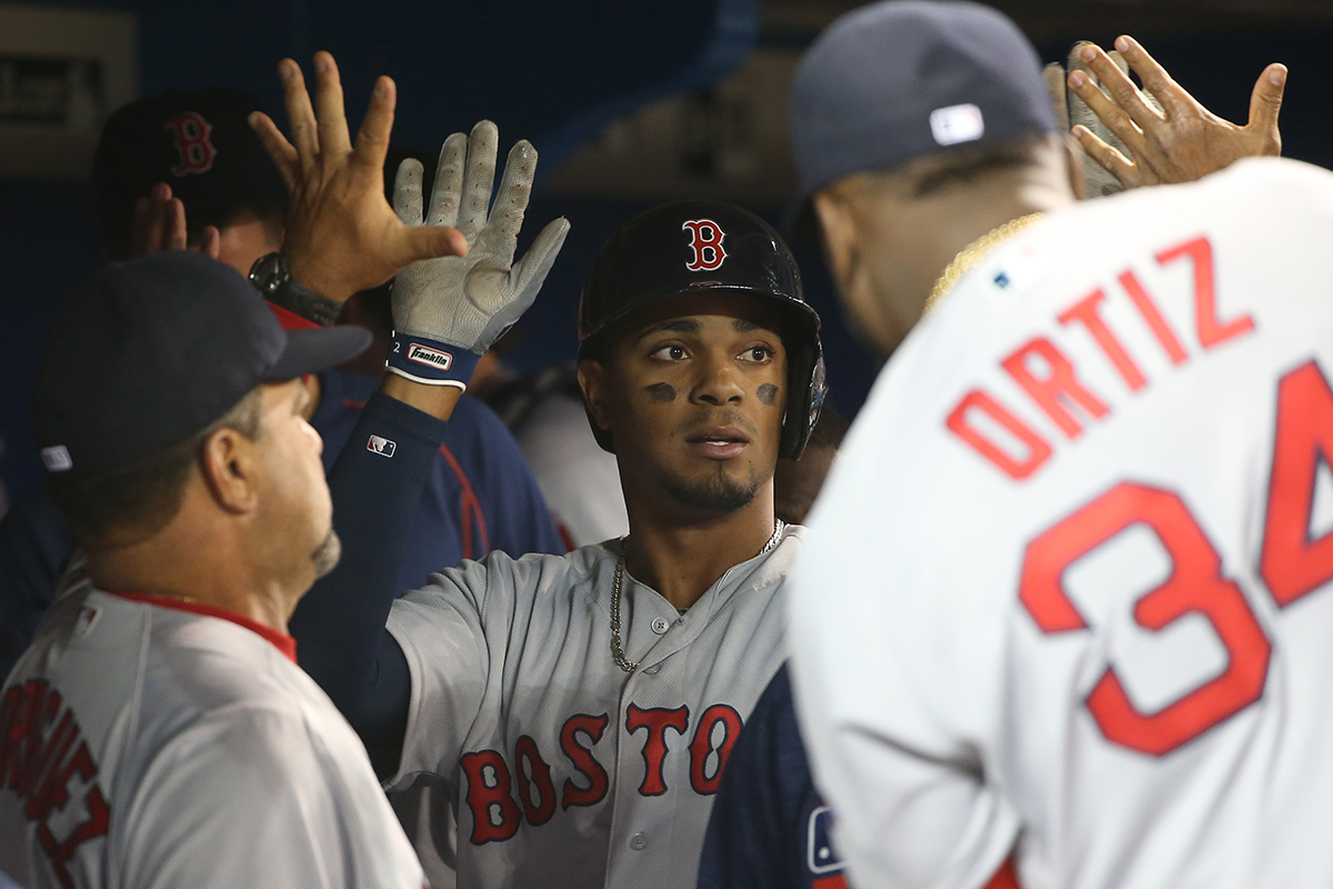 Xander Bogaerts #2 of the Boston Red Sox is congratulated by teammates in the dugout after scoring a run in the third inning during MLB game action against the Toronto Blue Jays on April 9, 2016 at Rogers Centre in Toronto, Ontario, Canada.