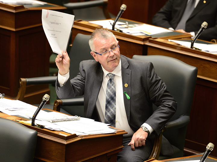 Ontario Labour Minister Kevin Flynn holds up papers in the legislature at Queen's Park in Toronto, Monday, May 25, 2015. 