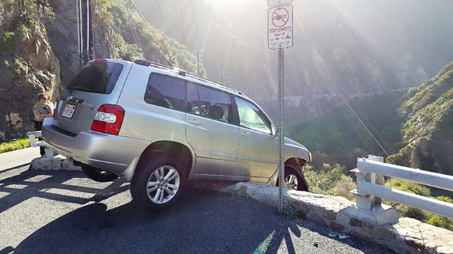 This Saturday, April 2, 2016 photo provided by the Los Angeles County Sheriff's Department shows an SUV that broke through a guardrail and nearly went over a cliff on Malibu Canyon Road in Malibu, Calif.