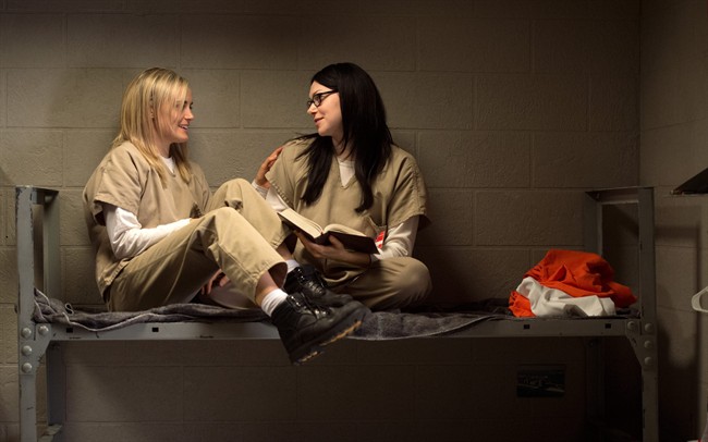 In this file image provided by Netflix, Taylor Schilling, left, and Laura Prepon appear in a scene from the Netflix original series, "Orange is the New Black." Netflix has been spending tons of money on new shows, and in sheer volume of new programming.
