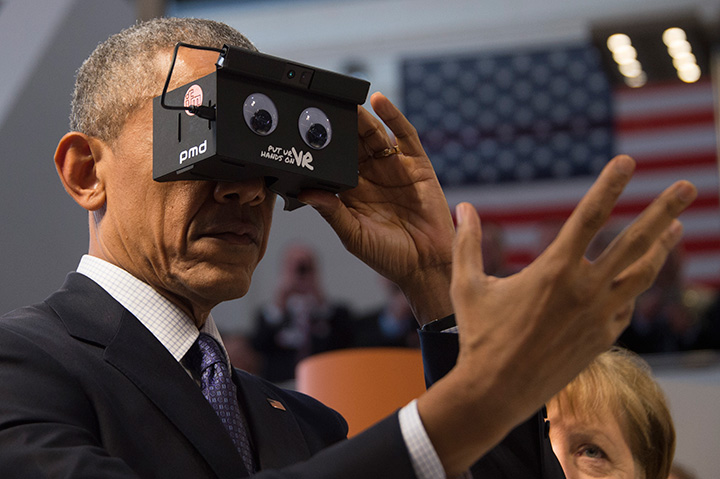 U.S. President Barack Obama looks through a virtual reality device at the booth of German automation company IFM electronics as he tours the Hanover industrial Fair in Germany on April 25, 2016.