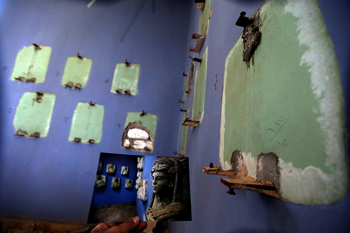 A picture taken on March 31, 2016 shows a photographer holding his picture of the museum of Palmyra taken on March 14, 2014 in front of what remains of the same spot after it was destroyed by Islamic State.