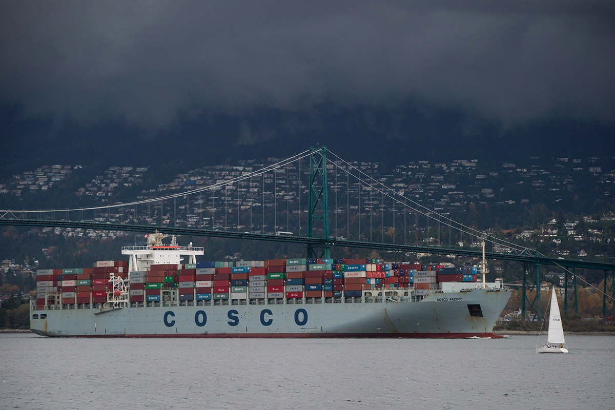 A sailboat leaves the harbour as the container ship Cosco Pacific, arriving from Prince Rupert, passes under the Lions Gate Bridge to dock at port in Vancouver, B.C., on Thursday November 6, 2014. 