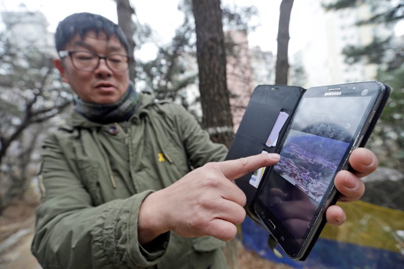 In this Jan. 28, 2016, photo, Choi Seung-woo shows an old photo of the Brothers Home, a mountainside institution where some of the worst human rights atrocities in modern South Korean history took place, in Busan, South Korea.