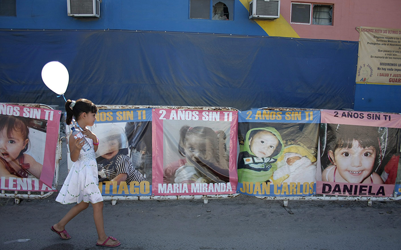 A girl walks by photographs of children who died during a fire at a day care in the city of Hermosillo, Mexico, Sunday June 5, 2011.  Sunday marks the two year anniversary of the ABC day care center fire that claimed the lives of 49 children in Hermosillo. 