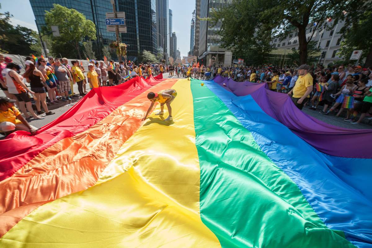 FILE: Revelers spread out a giant LGBT flag in the streets of Montreal during the Montreal Pride parade on August 16, 2015.