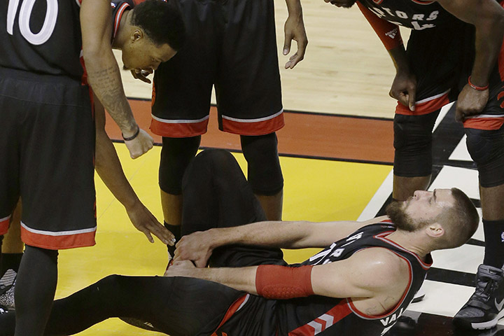 Toronto Raptors center Jonas Valanciunas (17) holds onto his right ankle as his teammates assist during the second half of Game 3 of an NBA second-round playoff basketball series against the Miami Heat, Saturday, May 7, 2016, in Miami.