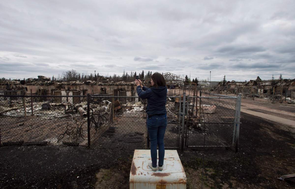 A reporter takes pictures of the wildfire destruction in the Abasands neighbourhood in Fort McMurray Monday, May 9, 2016.
