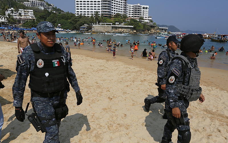 Federal police officer patrol Caleta beach crowded with local residents and tourists in Acapulco, Mexico, Friday, May 13, 2016. 