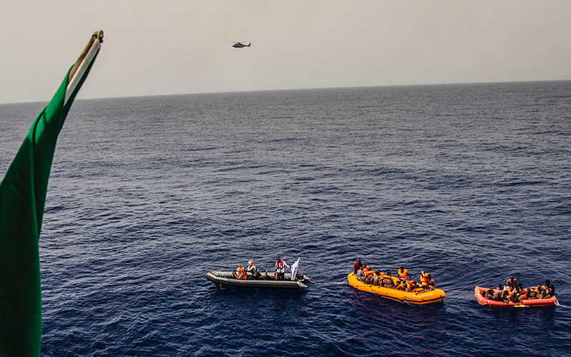 In this photo taken in the Mediterranean Sea, off the Libyan coast, Friday, May 27, 2016, rescuers tow migrants to the Italian Navy ship Vega, after the boat they were aboard sunk. 
