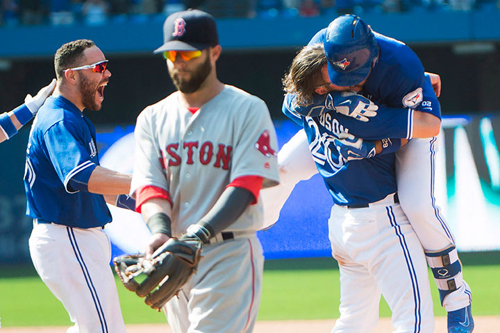 Toronto Blue Jays third baseman Josh Donaldson (20) and Toronto Blue Jays catcher Russell Martin (55) rush Toronto Blue Jays second baseman Devon Travis, back right, after travis hit the game-winning RBI, which Marin scored on, as Boston Red Sox second baseman Dustin Pedroia (15) looks on during ninth inning AL baseball action in Toronto on Saturday, May 28, 2016.