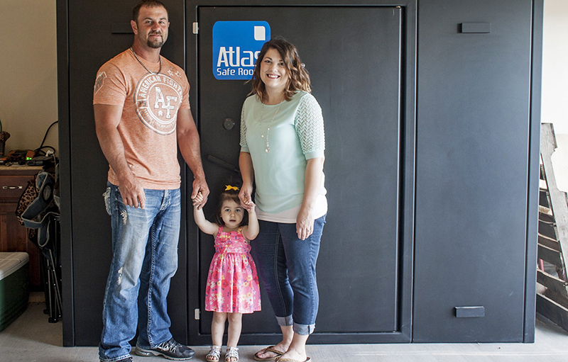 Ricky and Kayla Smith and their 2-year-old daughter Kailee pose in front of the tornado safe room built in their garage in Joplin, Mo., shortly after they got married in 2013.