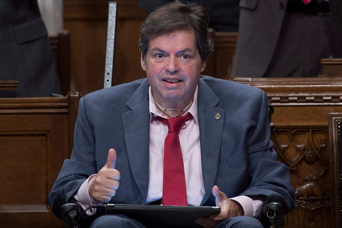 Ottawa-Vanier MP Mauril Belanger, who lives with ALS (also known as Lou Gherig's disease) gives the thumbs up as he receives applause after using a tablet with text-to-speech program to defend his proposed changes to neutralize gender in the lyrics to "O Canada" in the House of Commons.