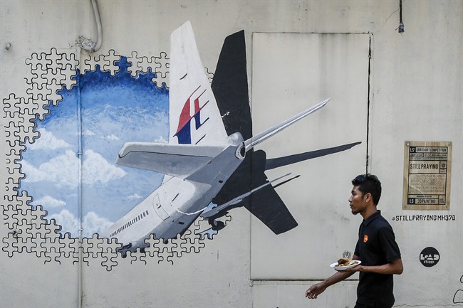 A waiter walks past a mural of flight MH370 in Shah Alam outside Kuala Lumpur, Malaysia. Malaysia's government said Thursday, May 12, 2016, that two more pieces of debris, discovered in South Africa and Rodrigues Island off Mauritius, were "almost certainly" from Flight 370, which mysteriously disappeared more than two years ago.