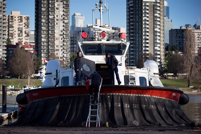 FILE - Members of the Canadian Coast Guard stand on a hovercraft docked outside the Kitsilano Coast Guard facility during an official visit by Minister of Fisheries and Oceans Hunter Tootoo in Vancouver in a December 16, 2015, file photo. Fisheries and Oceans Canada says starting this May long weekend, Kitsilano station will have four crews of three working 12-hour shifts. 